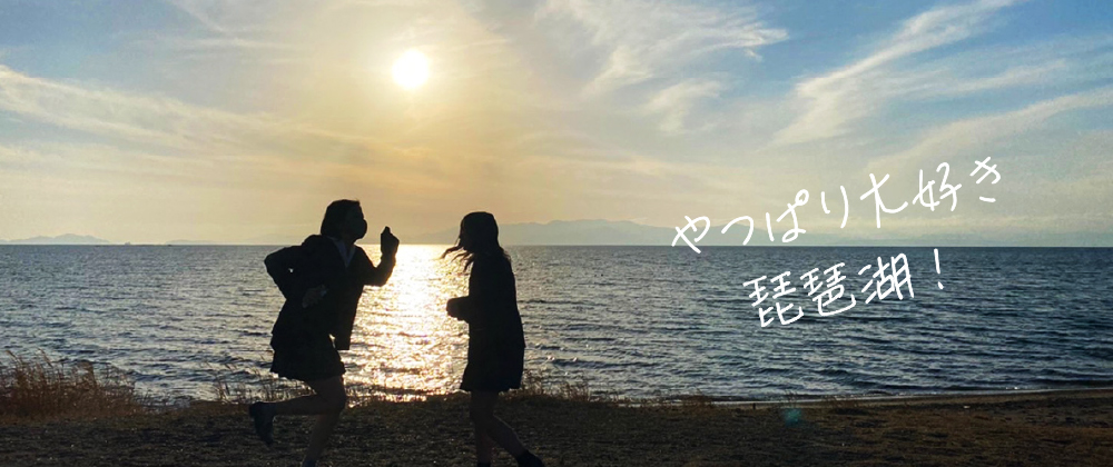 琵琶湖の景色の画像内右側に「やっぱり大好き琵琶湖!」の見出し。画像内左側に女子学生二人がはしゃいでいる様子。女子高生の真上に太陽がみえ、逆光で二人のシルエットは影になっている。